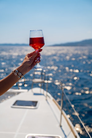 Female hand holding glass of wine on sea backgroundの写真素材