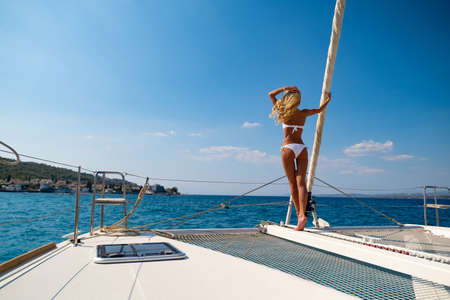 Woman in bikini tanning and relaxing on a summer catamaran sailing cruiseの写真素材
