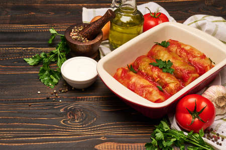 cabbage rolls stuffed with ground beef and rice with sour cream in a baking dish and ingredientsの写真素材