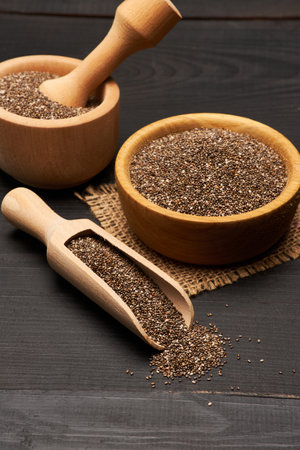 Organic natural chia seeds in wooden bowl close-up on dark wooden background or tableの写真素材