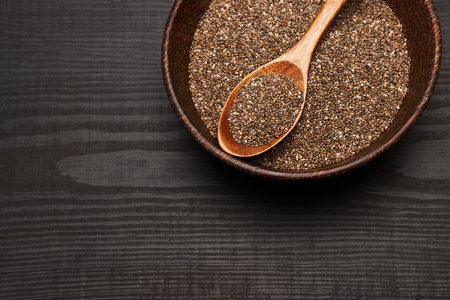 Organic natural chia seeds in wooden bowl close-up on dark wooden background or tableの写真素材