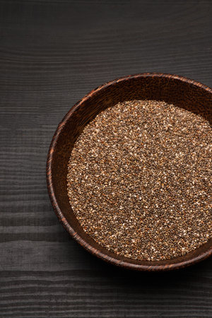 Organic natural chia seeds in wooden bowl close-up on dark wooden background or tableの写真素材