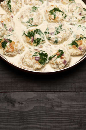 Delicious small meatballs with spinach in a creamy sauce in the frying panの写真素材