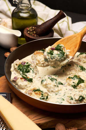Delicious small meatballs with spinach in a creamy sauce in the frying panの写真素材