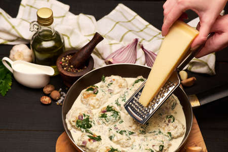 Delicious small meatballs with spinach in a creamy sauce in the frying panの写真素材