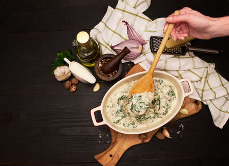 Delicious meatballs with spinach in a creamy sauce in baking dishの写真素材