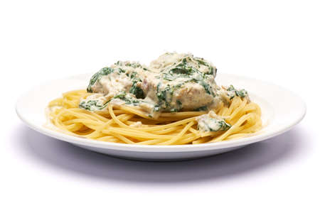 Portion of delicious meatballs with spinach in a creamy sauce and pastaの写真素材