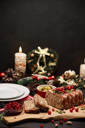 Traditional French terrine covered with bacon on dark wooden background with Christmas decorationsの写真素材