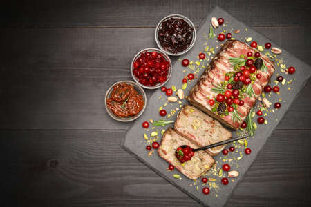 Traditional French terrine covered with bacon on dark wooden background with Christmas decorations
