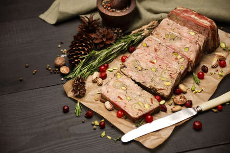 Sliced Traditional French terrine covered with bacon on dark wooden background