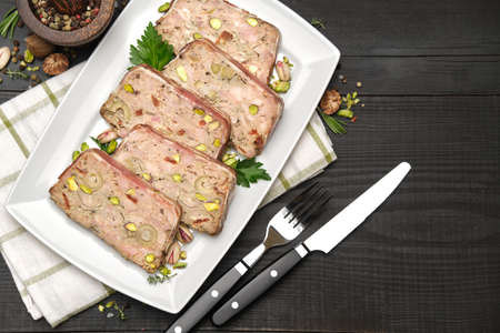 Sliced Traditional French terrine covered with bacon on dark wooden background