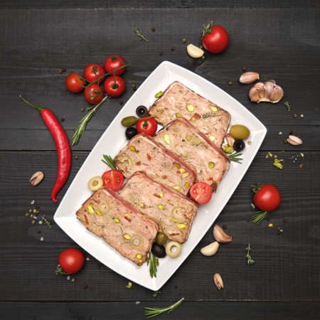 Sliced Traditional French terrine covered with bacon on dark wooden backgroundの写真素材