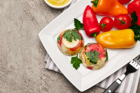Portion of delicious chicken aspic on a plate isolated on concrete table