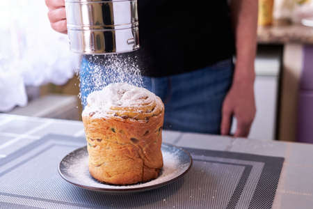 Adding sugar powder onto tasty Easter cake on a plateの写真素材