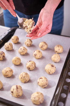 Woman holding ball of raw dough while making Chocolate chip cookies