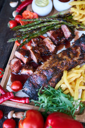 Barbecue pork ribs on wooden serving board on picnic table outdoorsの写真素材
