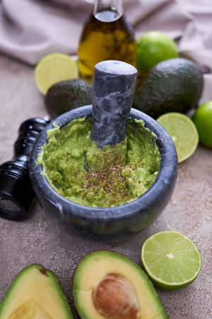 making guacamole - crushed avocado in marble mortar on grey concrete tableの写真素材