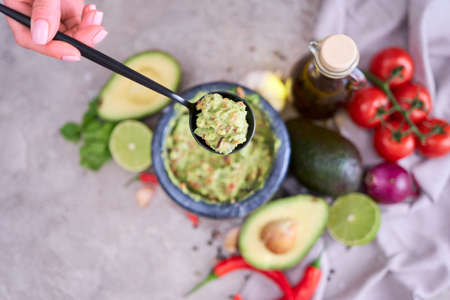 making guacamole - woman holding spoon with mixed minced ingredientsの写真素材