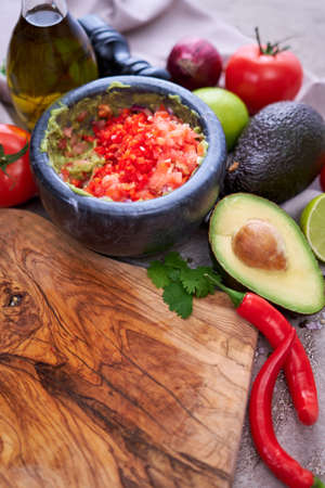 making guacamole - crushed avocado in marble mortar and ingredients