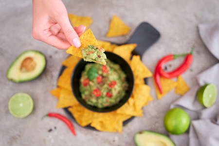 Guacamole dip with tortilla chips or nachos on black serving boardの写真素材