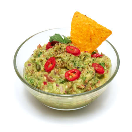 Healthy vegetarian organic guacamole Mexican dip sauce served in glass bowl with nachos or tortilla chips isolated on white backgroundの写真素材
