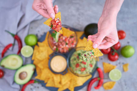 freshly made salsa and guacamole dip sauce with nacho chips on stone serving boardの写真素材