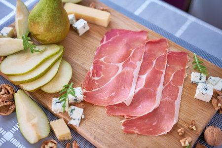 Jamon or prosciutto ham slices, Blue cheese, pears and walnuts on wooden boardの写真素材