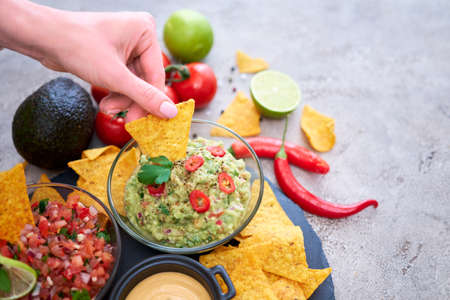 freshly made salsa and guacamole dip sauce with nacho chips on stone serving boardの写真素材