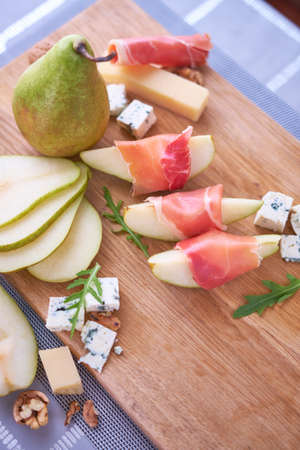 Jamon or prosciutto ham slices, Blue cheese, pears and walnuts on wooden boardの写真素材