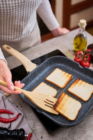Sliced bread fried on grill frying pan at domestic kitchen