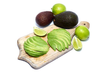 Sliced avocado fruit on wooden chopping board isolated on white background