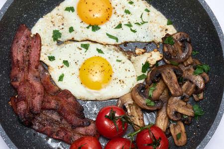 Fried eggs and bacon on a frying pan isolated on white backgroundの写真素材
