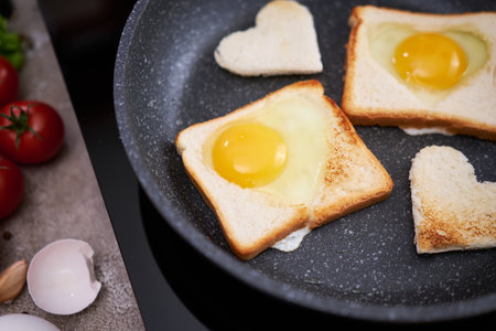 Fried egg Toasts with heart shaped holes on frying panの写真素材