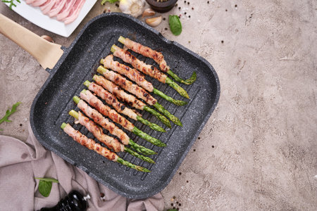 Healthy food - Asparagus wrapped with bacon and spices on grill panの写真素材