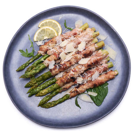Healthy food - Asparagus wrapped with bacon and spices on a plate isolated on white backgroundの写真素材