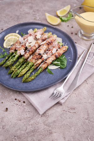 Healthy food - Asparagus wrapped with bacon and spices on a plateの写真素材
