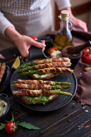 Tasty breakfast - toasts with cream cheese and Asparagus wrapped with bacon and spices on a plateの写真素材