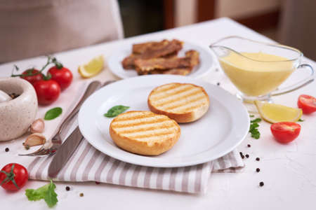 Grilled buns, bacon and Classic Hollandaise sauce of butter and egg yolks served in a gravy boat