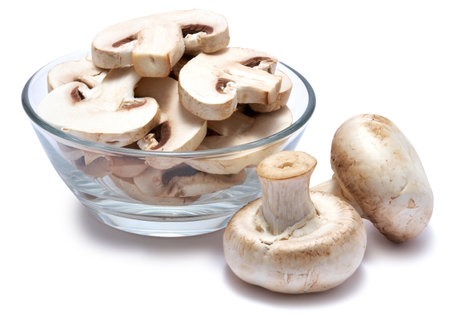 Sliced white champignon mushrooms in glass bowl isolated on white backgroundの写真素材