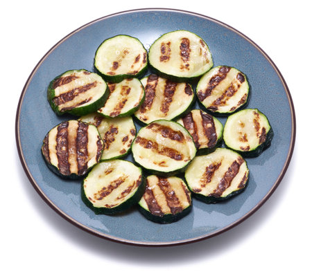 Slices of zucchini roasted on a grill with stripes from a grill isolated on white backgroundの写真素材