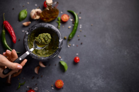 woman mixing green sauce in a stone marble mortarの写真素材