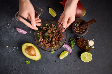 Woman mixing chopped tuna, cilantro and onion in a glass bowl cooking traditional tuna tartareの写真素材