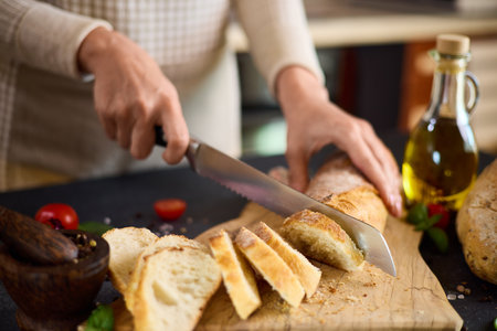 chef cutting Fresh bread on wooden cutting board on kitchen tableの写真素材