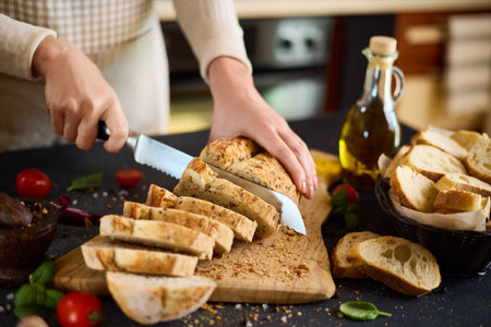 chef cutting Fresh bread on wooden cutting board on kitchen tableの写真素材