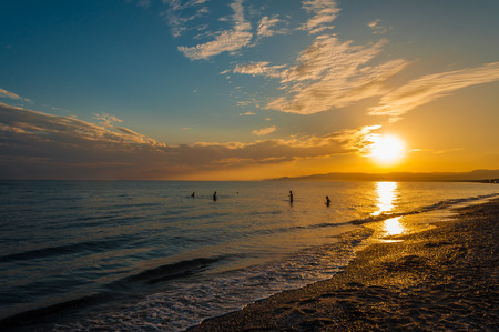 silhouette of four boys playing with a ball in the sea at the end of the dayの写真素材