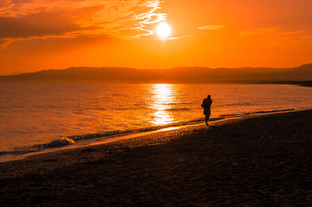 a man walking on the beach at the sunriseの写真素材