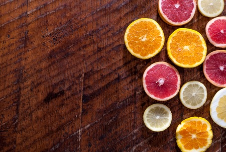 Sliced lemon, orange and punk grapefruit on wooden table with copy space
