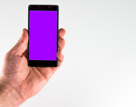 Closeup of male hand with a purple screen smartphone on white backgroundの写真素材