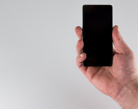 Closeup of male hand with a black screen smartphone on white backgroundの写真素材