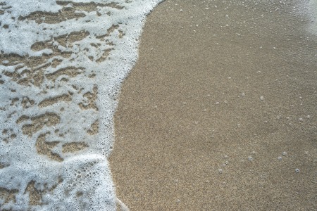 Closeup of waves on the beach sand in a sunny day of summer